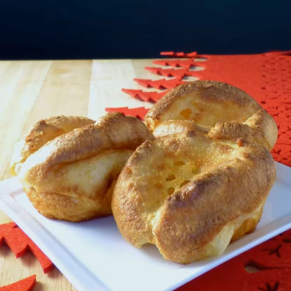 Three golden brown Yorkshire puddings on a plate.