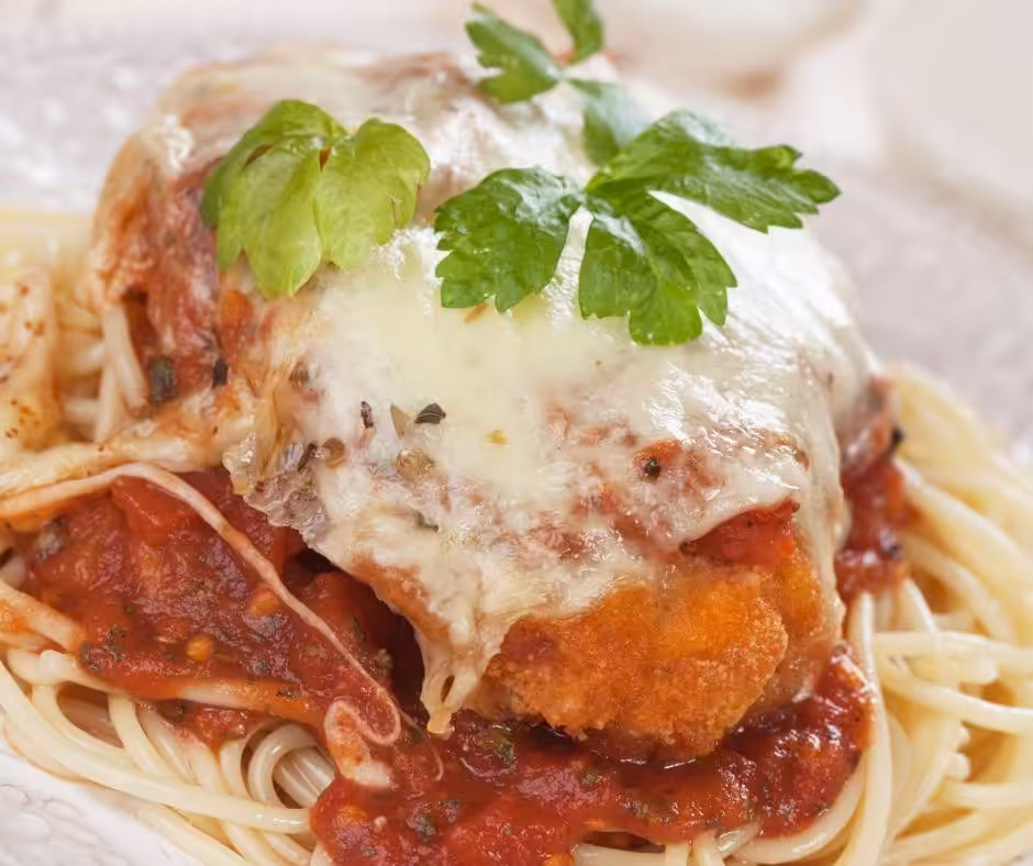 Breaded chicken covered in marinara sauce and melted mozzarella cheese on a bed of spaghetti.