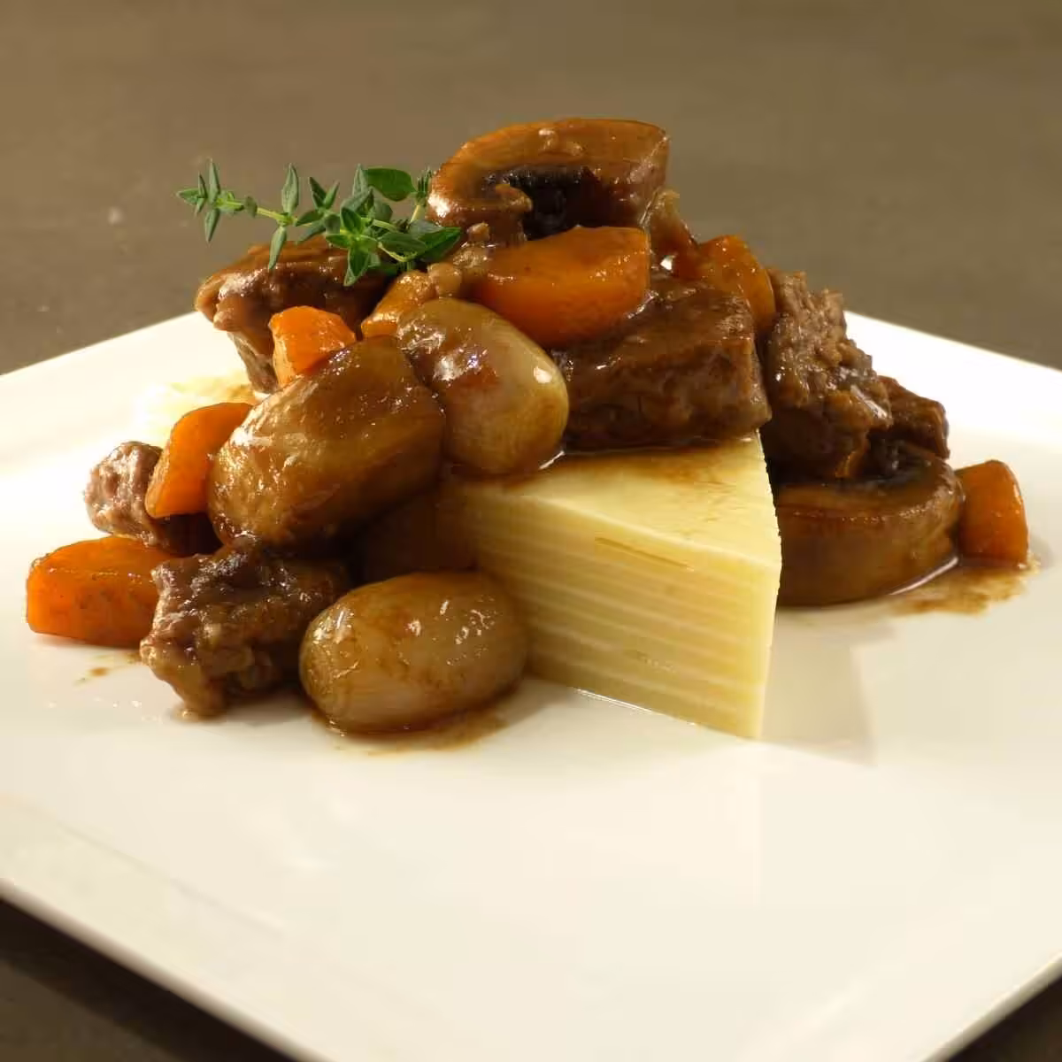 Closeup of a triangular piece of beef, mushroom and onion stew Inside Out Lasagne.